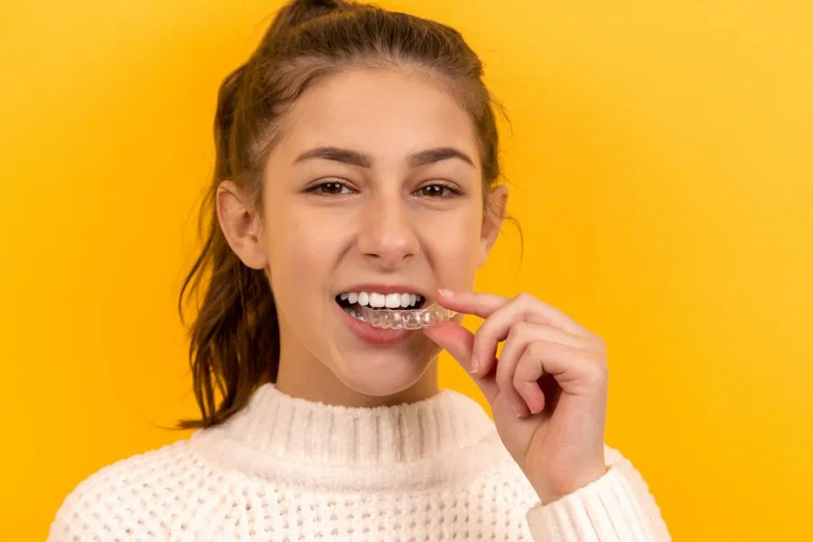 A smiling young woman brushing her teeth